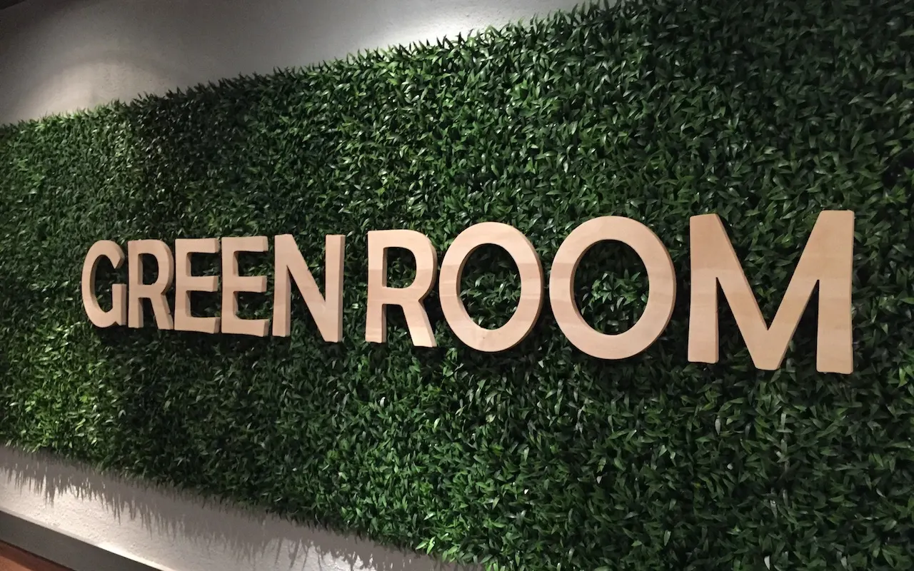 Løse trebokstaver «GREEN ROOM» montert på en grønn plantevegg